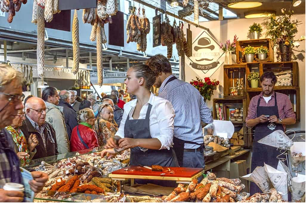  the market hall features a large open space that is filled with a wide variety of food stalls, shops, and restaurants. The stalls offer a range of fresh and local produce, including fruits, vegetables, meats, fish, and cheeses.