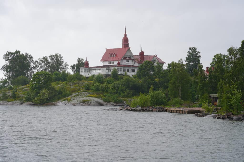building with a wraparound balcony, a red roof, and a steeple rising behind it.