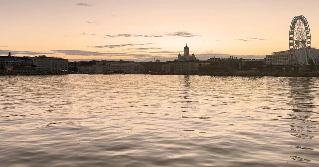 Helsinki's skyline at dusk, the cathedral dome and SkyWheel silhouetted over the water
