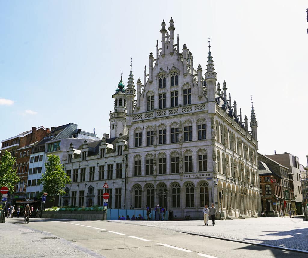 Ornate Gothic building with a turret, now home to The Fourth Hotel, beside Leuven's Grote Markt