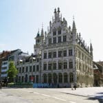Ornate Gothic building with a turret, now home to The Fourth Hotel, beside Leuven's Grote Markt
