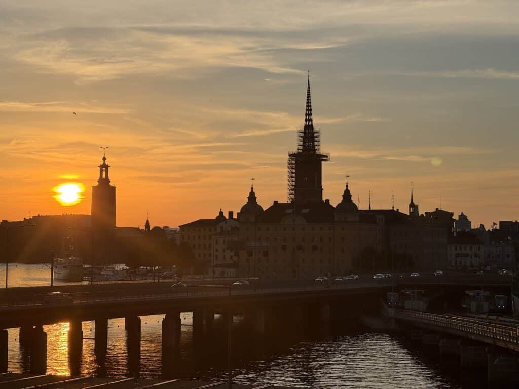 Silhouette of Riddarholmen Church spire and Stockholm City Hall tower at sunset