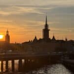 Silhouette of Riddarholmen Church spire and Stockholm City Hall tower at sunset
