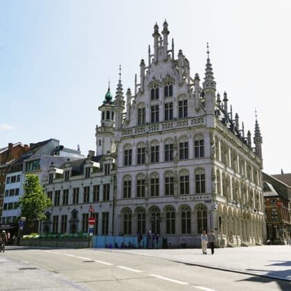 Ornate Gothic building with a turret, now home to The Fourth Hotel, beside Leuven's Grote Markt