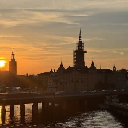 Silhouette of Riddarholmen Church spire and Stockholm City Hall tower at sunset